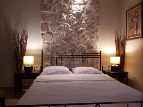 a bedroom with a bed with two lamps and a stone wall at Villa Del Lago Boutique Hotel in Kastoria