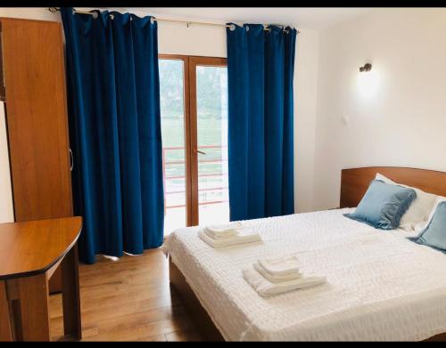 a bedroom with a bed with blue curtains and a window at Escape in Dubova