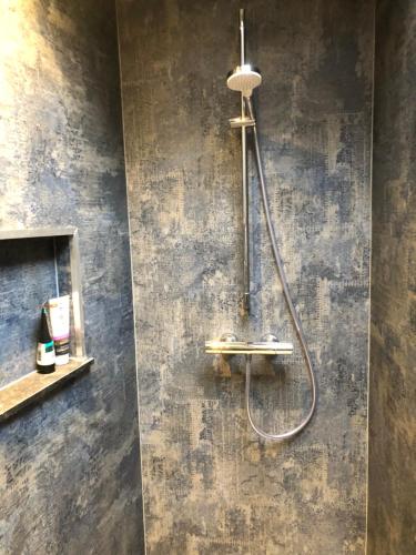 a shower in a bathroom with a concrete wall at Het Huis van de Wadden in Den Oever