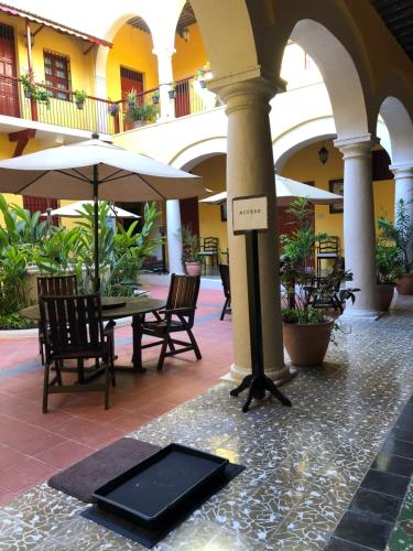 a table and chairs and an umbrella in a courtyard at Castelmar Hotel in Campeche