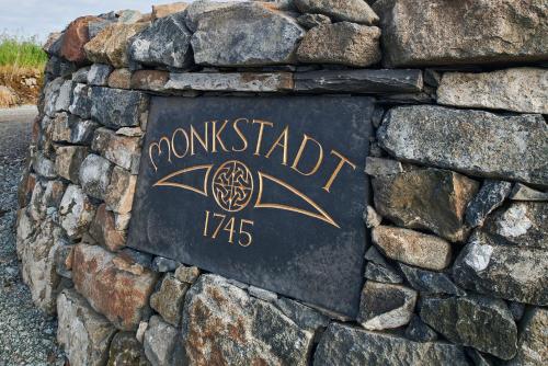 a stone wall with a sign on a rock wall at Monkstadt 1745 Restaurant with Rooms in Portree