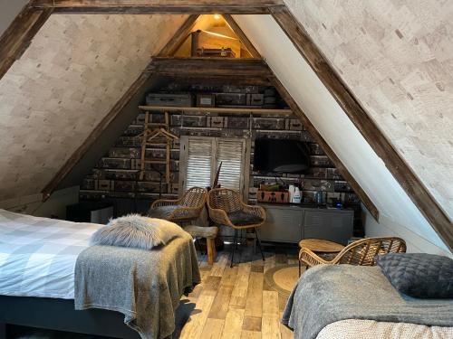 a attic bedroom with a bed and two chairs at Het Huis van de Wadden in Den Oever