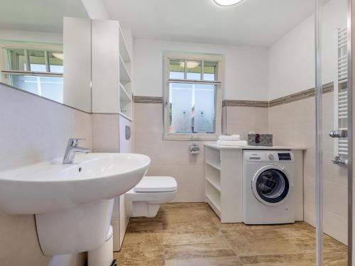 a white bathroom with a sink and a washing machine at Bernsteinsuite in Prerow