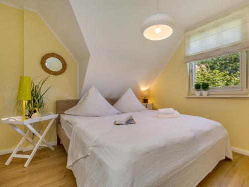 a bedroom with a large white bed and a window at Bernsteinsuite in Prerow