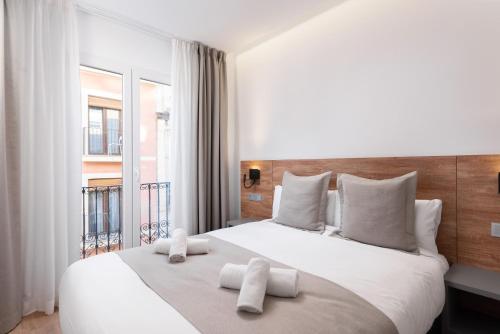 a bedroom with a large white bed with towels on it at VIL5 by Be Alicante in Alicante