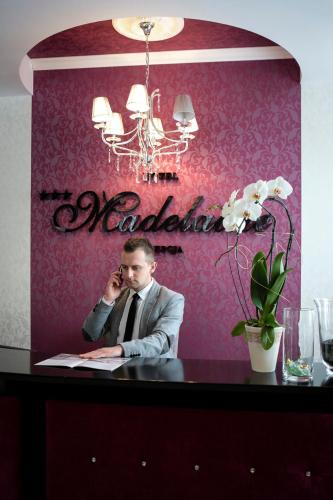 a man sitting at a table talking on a cell phone at Hotel Madelaine in Lwówek Śląski