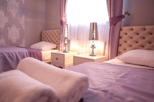 a bedroom with two beds and two lamps and a window at Hotel Madelaine in Lwówek Śląski