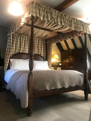 a canopy bed with white pillows in a bedroom at Bells Cottage in Alderton