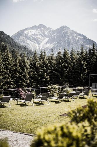 a group of chairs sitting in a field with a mountain at Verwöhn-Wellnesshotel Walserhof in Hirschegg