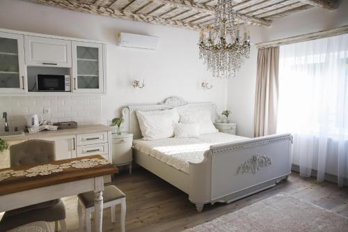 a white bedroom with a bed and a chandelier at BAB-LAK Apartman in Kisvárda