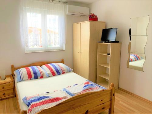 a small bedroom with a bed and a television at Pranjic Delux Guest House in Vodice