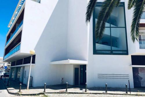 a white building with a palm tree in front of it at Vacations home Albufeira in Albufeira