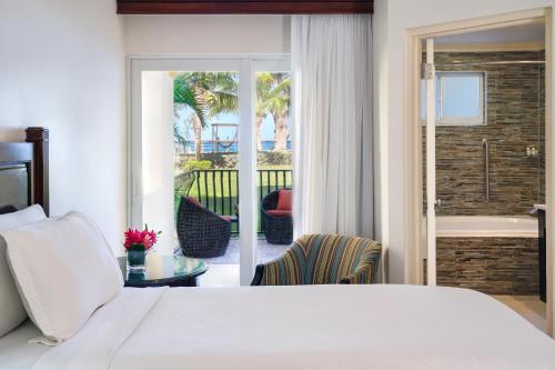 a bedroom with a bed and a balcony with a tub at Jewel Paradise Cove Adult Beach Resort & Spa in Runaway Bay