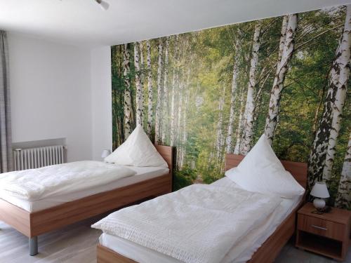 Pension Brandner في Altrandsberg: غرفة نوم بسريرين وجدار اشجار