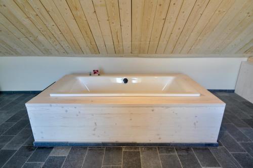 Cette chambre dispose d'une baignoire et d'un plafond en bois. dans l'établissement Ferienhaus Baustert, à Baustert