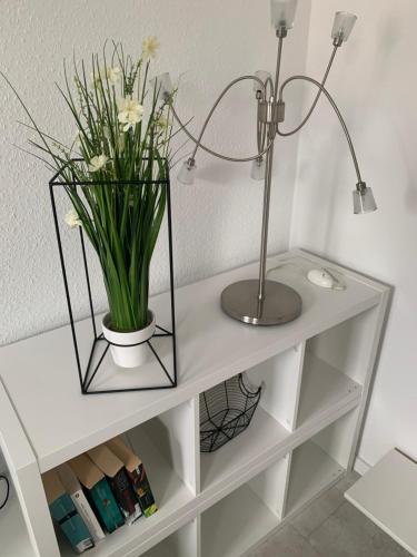 a white shelf with a vase of flowers on it at Barrierefrei - 24Std-CHECK-IN kontaktlos - Kingsize Bed - W-LAN - Parkplatz W 3 in Bückeburg