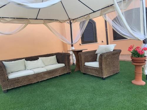 two wicker chairs and a couch under an umbrella at Villa Sarno in Montesilvano