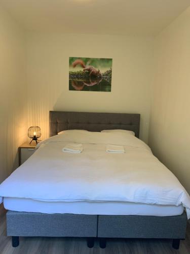 a bedroom with a large bed with white sheets at Bonte Specht: tot rust komen in de natuur! in Otterlo