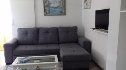 ein Wohnzimmer mit einem Sofa und einem TV in der Unterkunft La Pineda III in La Pineda