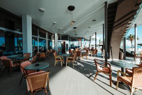 un restaurante con mesas, sillas y ventanas en the Loža - seaside festival hotel, en Novalja