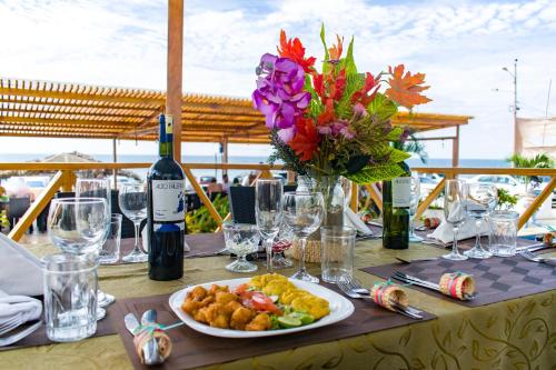 una mesa con un plato de comida y un jarrón de flores en Villa Kite, en Santa Marianita