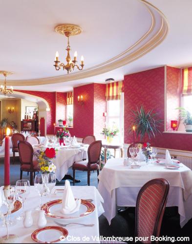 a restaurant with white tables and chairs and a chandelier at Clos de Vallombreuse, The Originals Relais in Douarnenez