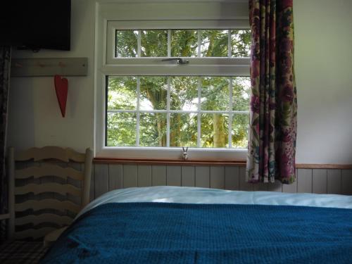 a bedroom with a bed and a window at The Owl Hoot in Ipstones