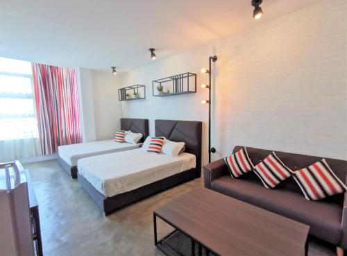ムアルにあるMWV Suite Room (MUAR)のベッド2台とソファが備わるホテルルームです。