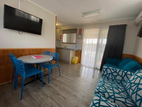 a living room with a table and chairs and a television at Twin Dolphins Holiday Park in Tuncurry