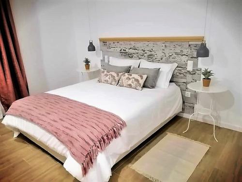 a bedroom with a large white bed with a brick wall at Olívale - Turismo Rural in Campo Maior
