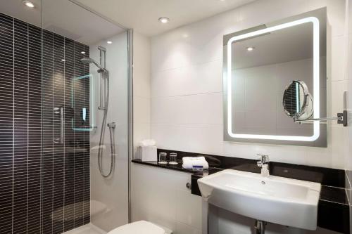 bagno con lavandino, doccia e specchio di Radisson Hotel and Conference Centre London Heathrow a Hillingdon
