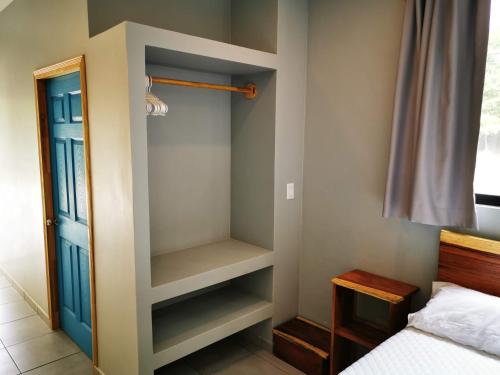 a bedroom with a closet with a bed and a blue door at Little Hawaii Avellanas in Playa Avellana