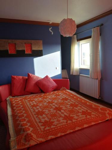 a bedroom with a red bed and a blue wall at Villa Porto de Mós near Fatima in Porto de Mós