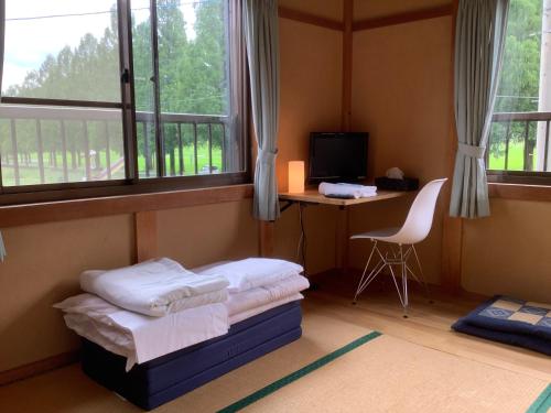 a bedroom with a bed and a desk and windows at Biwako Makino Hifumikan in Takashima