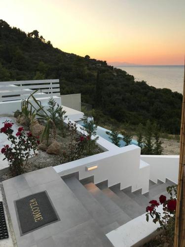 a sunset over the ocean from a white building with stairs at Zante Fiore Suites in Xirokástellon