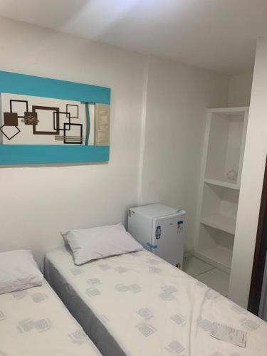 a bedroom with two beds and a painting on the wall at Zacas House ITAPOA in Vila Velha