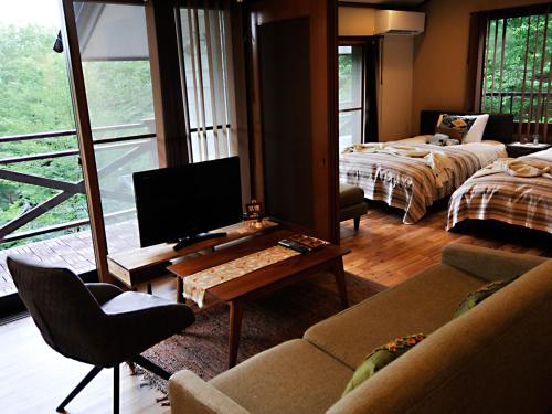 a living room with a tv and a couch and a desk at 大人スイート 那須高原 結 cottage in Nasu