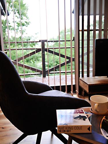 a black chair sitting in a living room with a table at 大人スイート 那須高原 結 cottage in Nasu