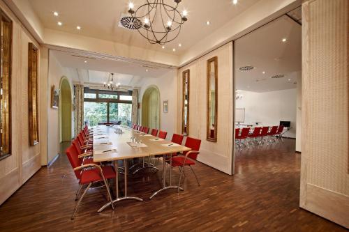 a dining room with a long table and red chairs at Hotel Hirschen in Freiburg-Lehen in Freiburg im Breisgau