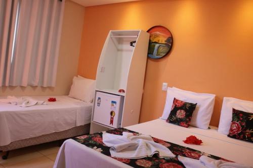 a room with two beds and a mirror on the wall at Pousada Málaga in Porto De Galinhas