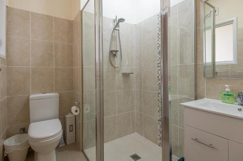 a bathroom with a shower and a toilet and a sink at Batehaven Beach House in Batehaven