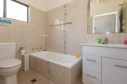 uma casa de banho com uma banheira, um WC e um lavatório. em Batehaven Beach House em Batehaven