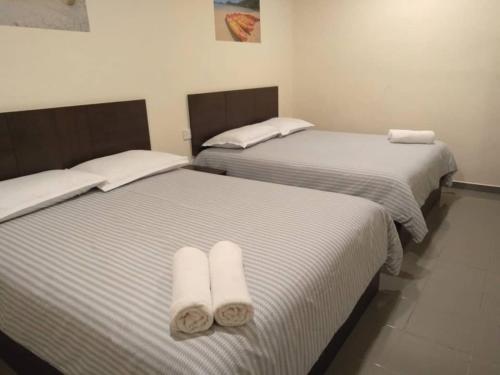 duas camas num quarto com lençóis brancos e toalhas em Pangkor 88 Villa Jia Yuan 邦咯岛家苑海滩度假别墅 em Kampong Pasir Bogak