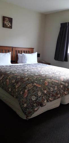 a bed in a hotel room with a blanket on it at Denton Park Motel in Christchurch