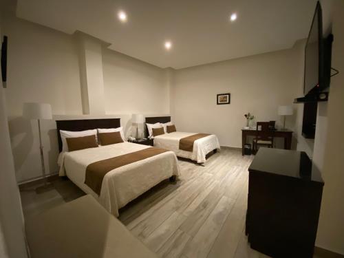 a hotel room with two beds and a table at Hotel Casa Faroles Centro Histórico in Zacatecas