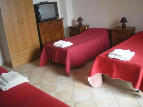 a room with two beds with red sheets and a tv at B&B Da Matì in Campobello di Mazara