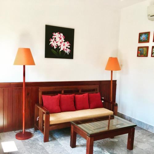 a couch with red pillows in a room with two lamps at Villa Orchid Garden Riverside Hoi An in Hoi An