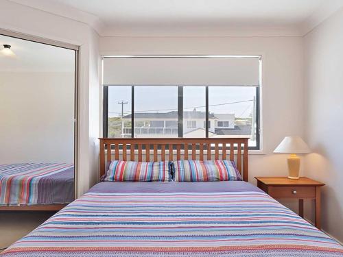 a bedroom with a bed and a large window at Ocean Views air conditioned luxury with beautiful ocean views in Anna Bay