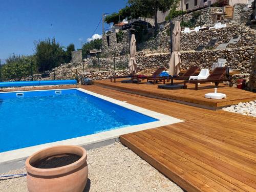una piscina con sedie e ombrelloni su una terrazza di legno di Vita Vacation Home a Ustrine