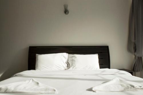 a bed with white sheets and two towels on it at Nattidaplace Hotel Chiangmai in Chiang Mai